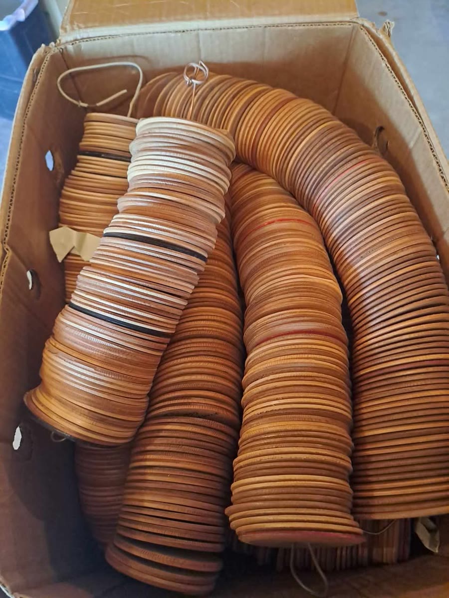 A cardboard box packed with hundreds of wooden soundhole discs threaded on wires